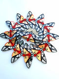 12 tiger moth necklaces arranged in a circle with one in the centre