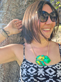woman with short dark hair standing in the sun wearing the red eyed tree frog necklace