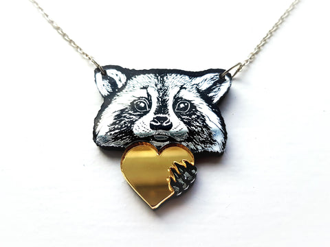 acrylic Raccoon necklace. Silver raccoon holding a gold heart.