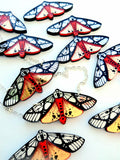 Ten of the tiger moth necklaces against a white background