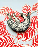 sloth necklace against colourful background
